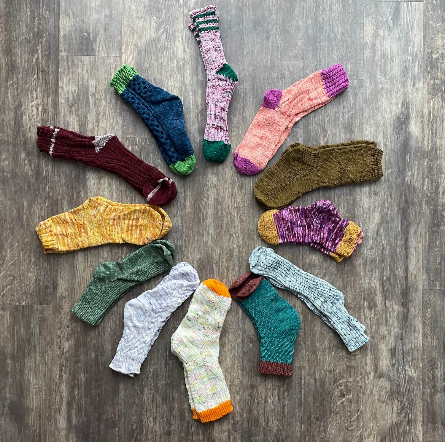 12 pairs of socks of varying styles and colors seen from above in the layout of a clock, each pair unique and clock number it's at matches the month in which they were made